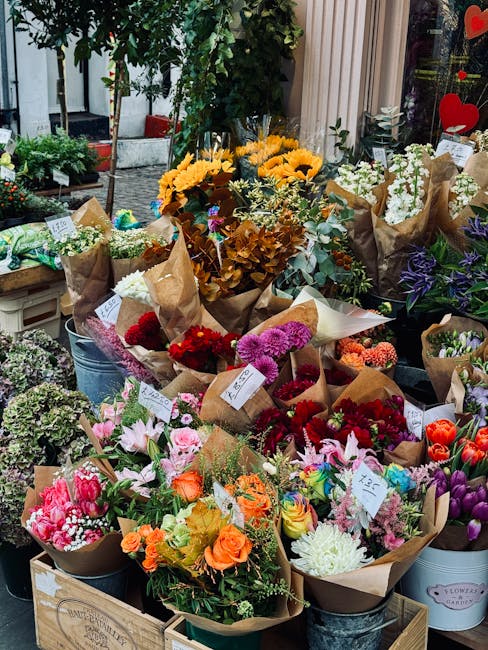 A vibrant display of fresh flowers arranged in various bouquets at a flower shop, Flowers Northolt. The arrangement includes bright yellow sunflowers, clusters of purple and white blooms, and an assor